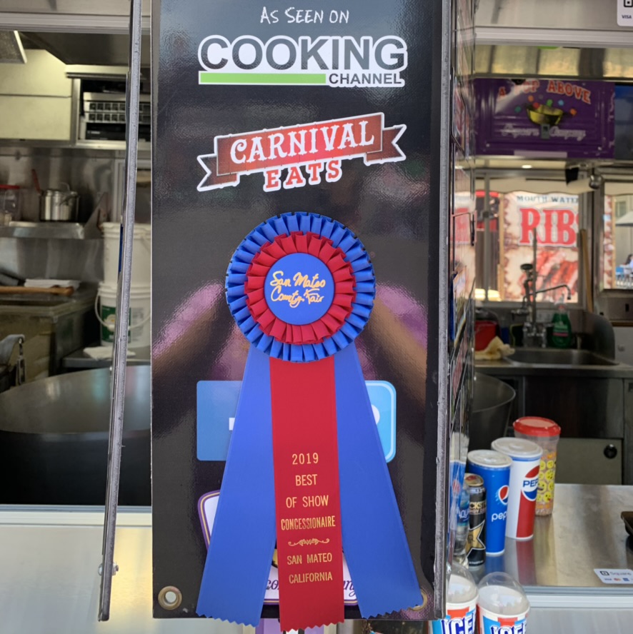 A Pop Above’s 2019 San Mateo County Fair Best of Show Concessionaire ribbon displayed on the stand